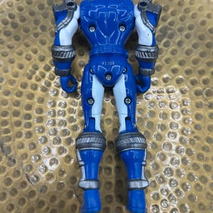 K&ouml;nnte beinhalten: Eine blaue Actionfigur mit wei&szlig;en und silbernen Akzenten. Die Figur hat einen Helm, r&uuml;stungs&auml;hnliche Details und bewegliche Gelenke. Die Nummer "41708" ist auf der R&uuml;ckseite der Figur aufgedruckt. Das Spielzeug ist aus Kunststoff.