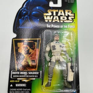 May include: A Star Wars "The Power of the Force" action figure of a Hoth Rebel Soldier, packaged on a green and black card. The figure is in a clear plastic case. The card features Darth Vader and the text "HOTH REBEL SOLDIER".
