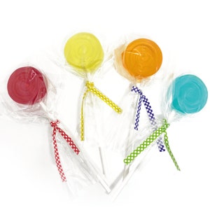 May include: Five colorful lollipops wrapped in clear plastic with polka dot ribbon ties. The lollipops are red, yellow, orange, blue, and green.