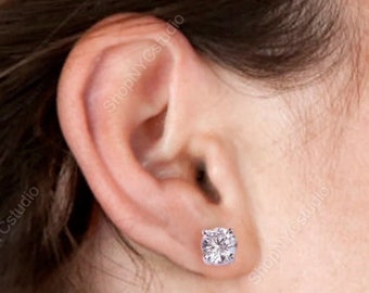 May include: A close-up of a person's ear with a small, round, clear diamond stud earring.