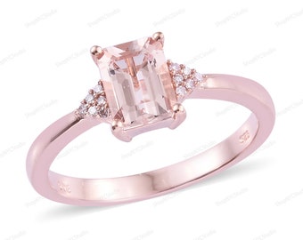 May include: A rose gold ring featuring a light pink morganite gemstone in an emerald cut setting. The ring is accented with small round diamonds on the sides.
