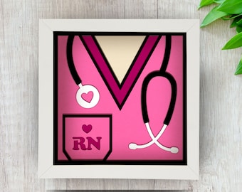 May include: A framed illustration of a pink nurse's uniform with a stethoscope and the letters "RN" on the pocket.