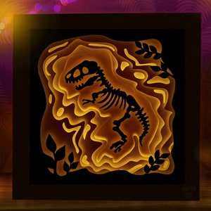 Pode incluir: Uma moldura de madeira preta com um design de arte em papel 3D em camadas de um esqueleto de dinossauro. O dinossauro &eacute; iluminado por tr&aacute;s, criando um efeito brilhante. O fundo &eacute; marrom escuro com um padr&atilde;o texturizado.