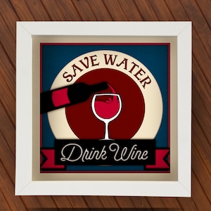 May include: A framed print with a white border features a wine-themed design. The artwork includes a wine bottle pouring into a glass, set against a blue and red background. The text reads "Save Water Drink Wine."