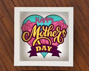 Może przedstawiać: Biała, oprawiona, warstwowa praca na papierze z motywem w kształcie serca. Grafika zawiera napis "Happy Mother's Day" w kolorze żółtym i różowym, z różowymi różami i fioletowym banerem. Tło jest turkusowe.