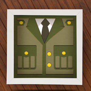 May include: A framed papercraft of a green military uniform with yellow buttons and a black tie.