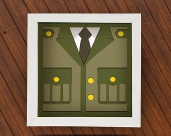 May include: A framed papercraft of a green military uniform with yellow buttons and a black tie.