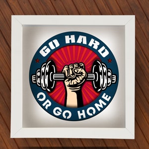Puede incluir: Póster motivacional enmarcado en blanco con un círculo azul y rayos rojos y blancos. El círculo tiene el texto "Go Hard or Go Home" y una ilustración en blanco y negro de una mano levantando una mancuerna.