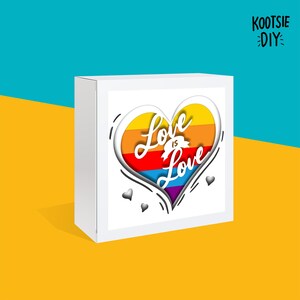 May include: White box with a rainbow heart design and the text "Love is Love" inside. The box is on a yellow surface with the text "KOOтSIE DIY" in the top right corner.