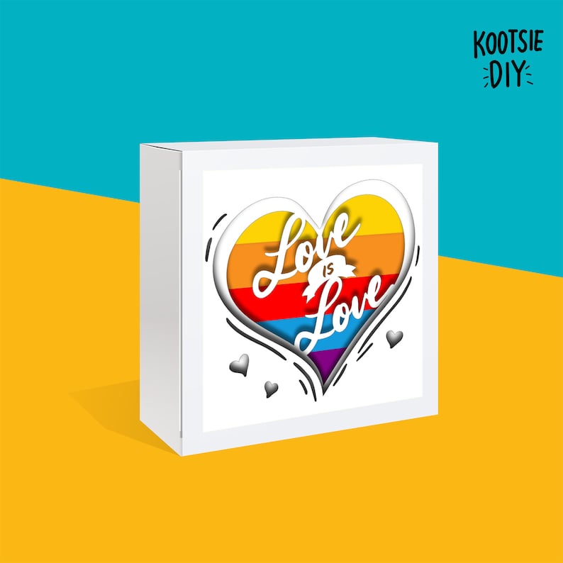 May include: White box with a rainbow heart design and the text "Love is Love" inside. The box is on a yellow surface with the text "KOOтSIE DIY" in the top right corner.