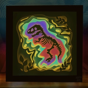 Pode incluir: Uma pe&ccedil;a de arte em papel 3D emoldurada que retrata um esqueleto de dinossauro em um fundo colorido e em camadas. O dinossauro &eacute; um T-Rex com uma silhueta preta e ossos brancos. O fundo &eacute; uma mistura vibrante de verde, azul, roxo e amarelo.