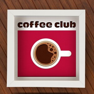 Könnte beinhalten: Weißer Rahmen mit rotem Hintergrund und dem Text "coffee club". Eine weiße Kaffeetasse mit braunem Kaffee und Schaum befindet sich in der Mitte des Rahmens.