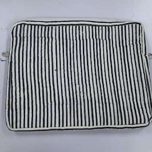 Op de afbeelding: Een laptophoes met witte en zwarte strepen en een ritssluiting.