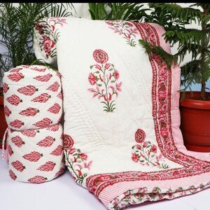 Puede incluir: Edred&oacute;n de algod&oacute;n blanco con estampado floral rosa. El edred&oacute;n est&aacute; doblado y enrollado, mostrando el patr&oacute;n floral en la tela. El edred&oacute;n est&aacute; hecho de algod&oacute;n suave y ligero, perfecto para climas c&aacute;lidos.