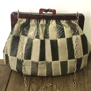 Può includere: Una pochette vintage in pelle di serpente marrone e beige con un motivo a scacchi. La pochette ha una cornice in plastica marrone con una catena dorata.