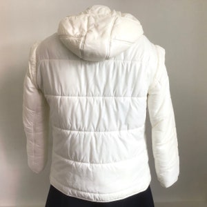 May include: White hooded puffer jacket with a quilted design.