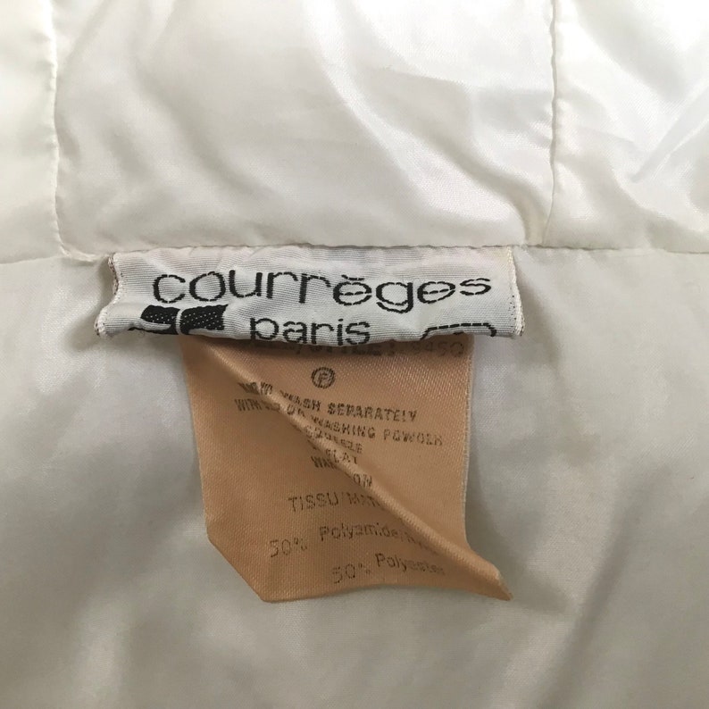 May include: A white label with black text that reads "courr&egrave;ges paris" and a smaller label with instructions for washing and fabric content. The fabric content is 50% Polyamide and 50% Polyester.