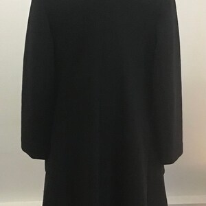 Pu&ograve; includere: Un cappotto di lana nero con un colletto classico e maniche lunghe. Il cappotto &egrave; sagomato e ha una silhouette aderente.