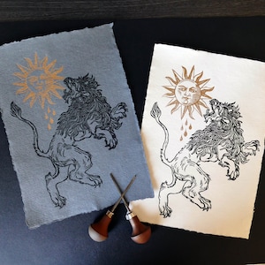 Linogravure impression papier coton gris Lion mangeant le soleil Alchimie | Lion mangeant le soleil linogravure Décoration murale dorée et noire imprimée à la main