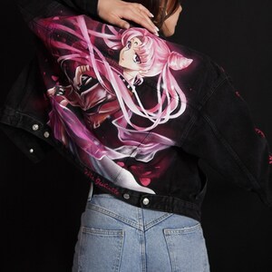 May include: A black denim jacket with a pink and purple anime character painted on the back. The character is a woman with long pink hair and a crown. The text "Via Juliette" is written on the bottom of the jacket.