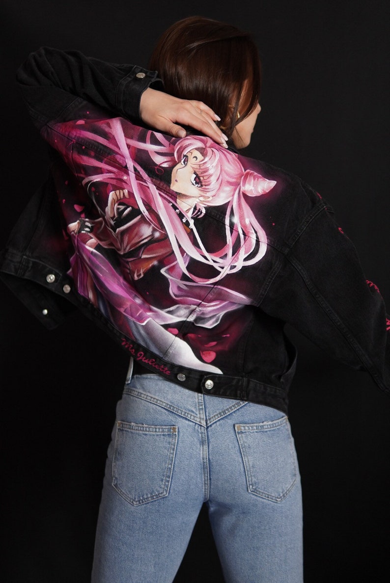 May include: A black denim jacket with a pink and purple anime character painted on the back. The character is a woman with long pink hair and a crown. The text "Via Juliette" is written on the bottom of the jacket.