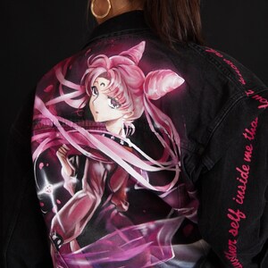 May include: Black denim jacket with a pink and purple anime character painted on the back. The text "another self inside me than" is written on the right sleeve in pink.