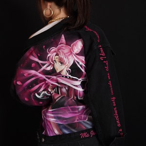 May include: Black denim jacket with a pink and purple anime character printed on the back. The jacket has pink text on the sleeve that reads "There's another self inside me that I don't", and "Ms. Ju" on the bottom.