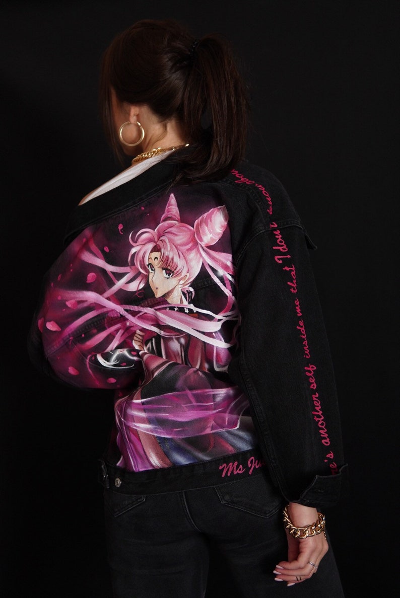 May include: Black denim jacket with a pink and purple anime character printed on the back. The jacket has pink text on the sleeve that reads "There's another self inside me that I don't", and "Ms. Ju" on the bottom.