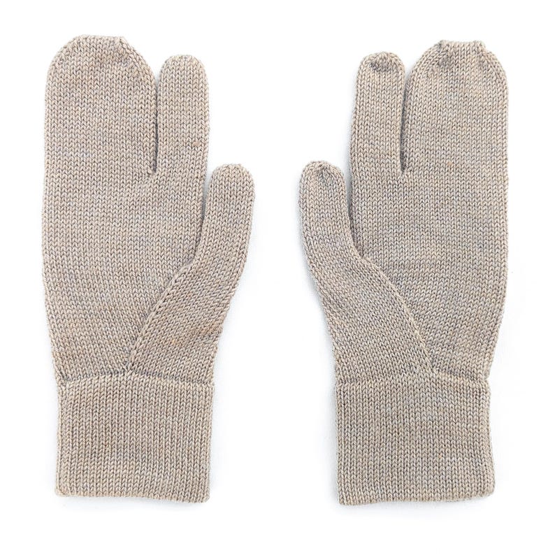 May include: A pair of light beige knitted gloves with a separate compartment for the thumb and index finger. The gloves have a ribbed cuff and are made of a textured yarn. The gloves are displayed on a white background.