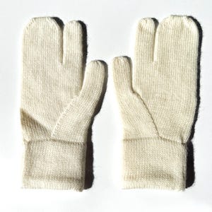 May include: A pair of off-white, knitted gloves with a split for the big toe. The gloves have a ribbed cuff and a separate section for the thumb. The gloves are made of a soft, textured material.