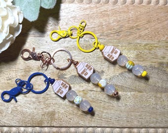 May include: Keychains with a milk carton design, featuring a variety of colors. Each keychain has a different colored clasp and ring, with beaded accents in shades of white, yellow, and blue. The milk carton design has Japanese text.