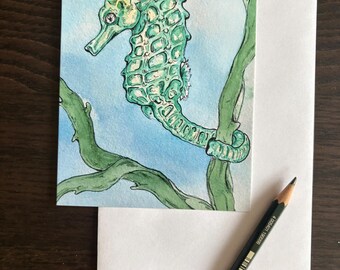 Tarjeta postal con diseño de caballito de mar verde, tamaño A6, con pintura en acuarela.
