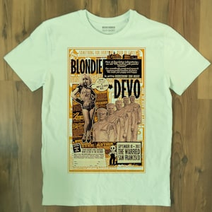 Op de afbeelding: Een lichtblauw T-shirt met een gele en zwarte print van een concertposter met Blondie en Devo. De poster bevat de tekst "Something for Everyone - Pain of Girls" en "Don't Roof Rack Me, Bro".