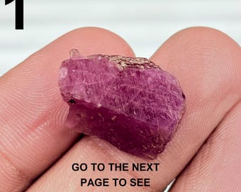 Op de afbeelding: Een ruwe robijn edelsteen met een dieproze kleur. De steen wordt in een hand gehouden, met het zwarte nummer "1" in de linkerbovenhoek. De tekst onderaan luidt "GO TO THE NEXT PAGE TO SEE MORE OPTIOUNS".