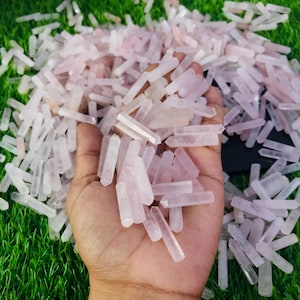 Op de afbeelding: Een grote stapel roze rozenkwarts kristallen punten. De punten zijn allemaal ongeveer 2,5 tot 5 cm lang en hebben een natuurlijke, ruwe afwerking.