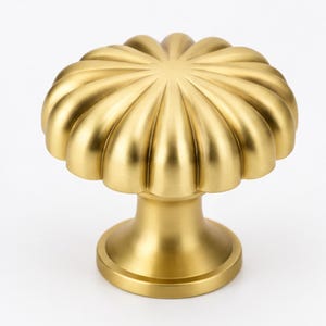 May include: A brushed gold cabinet knob featuring a circular, fluted design with radiating ridges that extend from the center to the outer edge. The knob has a smooth, matte metallic finish and a cylindrical base that flares out at the bottom.