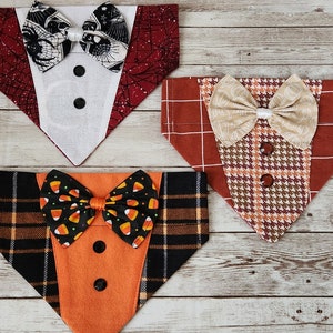 May include: Three dog bandanas with tuxedo designs. The bandanas are made of different fabrics and feature various bow ties. One bandana is red with black spiderwebs, another is orange with black and white plaid, and the last is brown with a tan bow tie.