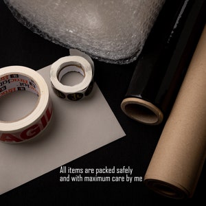 K&ouml;nnte beinhalten: Nahaufnahme von Verpackungsmaterial, darunter Luftpolsterfolie, Klebeband und braune Papierrollen. Das Klebeband tr&auml;gt den Aufdruck "AGIL" und der Text "Brackat" wird auf dem Klebeband wiederholt.