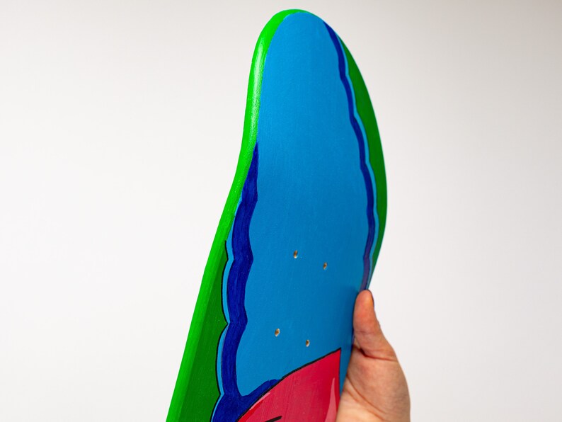 K&ouml;nnte beinhalten: Ein blaues, gr&uuml;nes und rotes Skateboard-Deck mit einem wellenf&ouml;rmigen Design. Das Deck ist aus Holz und hat eine glatte Oberfl&auml;che.