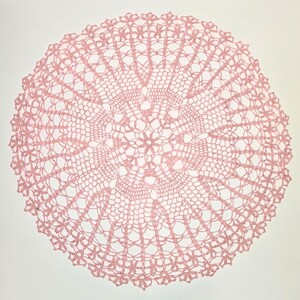 Puede incluir: Un delicado encaje de ganchillo rosa con un dise&ntilde;o circular. El encaje tiene un centro con un patr&oacute;n floral y un intrincado encaje alrededor de los bordes.