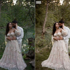 May include: A woman in an off-the-shoulder, floral-embroidered wedding dress stands with a man in a white shirt. The dress is a light beige color with delicate floral patterns. The couple is in a natural outdoor setting with trees and greenery.