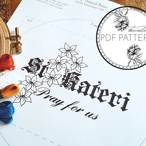 Könnte beinhalten: Ein schwarz-weißes Stickmuster für ein Kreuzstichdesign mit den Worten "Si Cateri Pray for us" umgeben von stilisierten Blumen. Das Muster ist auf einem weißen Blatt Papier mit einem 17,8 cm großen Kreis darauf gedruckt.