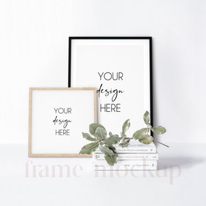 May include: Two picture frames, one black and one wood, with the text "YOUR design HERE" inside each frame. The frames are on a white surface with a stack of books and a green plant.