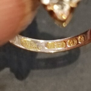May include: Close-up of the inside of a gold ring with the inscription "925" and "9ct" on the band.