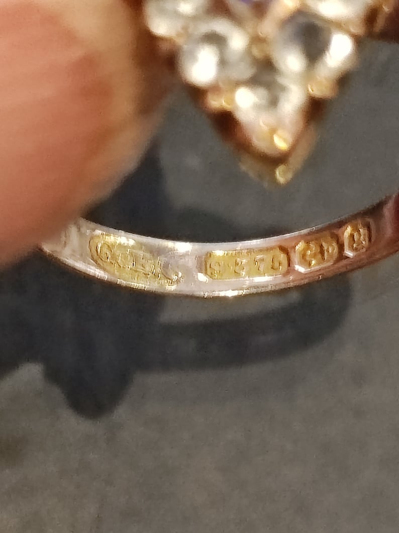 May include: Close-up of the inside of a gold ring with the inscription "925" and "9ct" on the band.