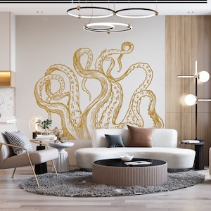 May include: A contemporary living room with a large gold octopus wall decal. The room includes a white sofa, a round coffee table, and a grey rug. A gold-framed chair and a side table with a lamp are also visible.