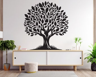 May include: A black and white silhouette of a tree with a thick trunk and many branches with leaves. The tree is on a white wall with a wooden floor and a white cabinet with a light wood top.