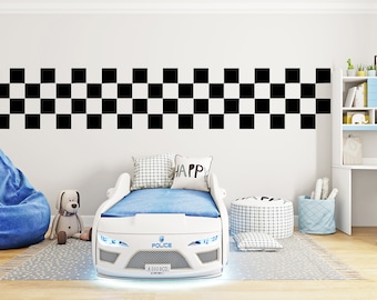 May include: White race car bed frame with blue and white bedding, a blue bean bag chair, and a stuffed dog. The bed frame has a black and white checkered pattern on the headboard and the words "Police" and "4000 BCD" on the front.