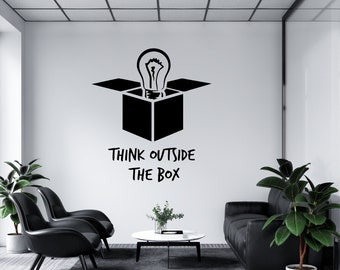 Może przedstawiać: Czarno-biały grafik przedstawiający żarówkę wyłaniającą się z otwartego pudełka z tekstem "Think outside the box". Grafika znajduje się na białej ścianie w biurze z dwoma czarnymi krzesłami i czarną sofą.