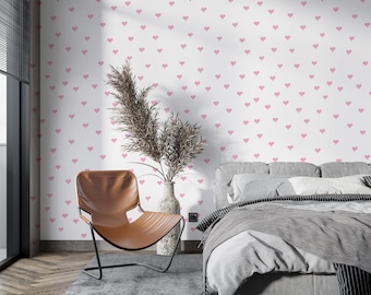May include: A bedroom with a white wall covered in a pink heart pattern wallpaper. A brown leather chair and a gray bed with white bedding are in the room.